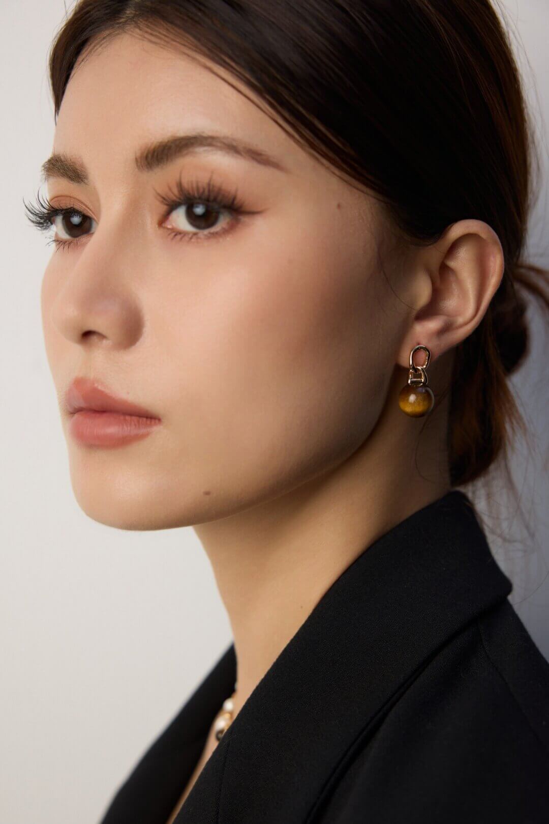 Close-up of a person wearing gold earrings with a neutral background