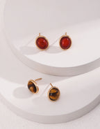 Pair of gold earrings with red and amber stones on a white background
