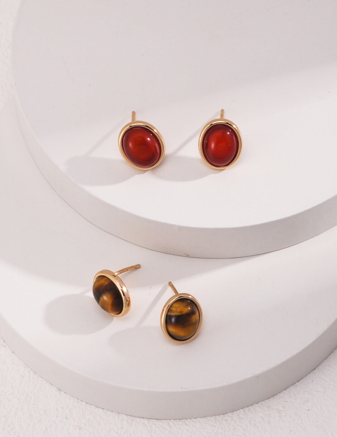 Pair of gold earrings with red and amber stones on a white background