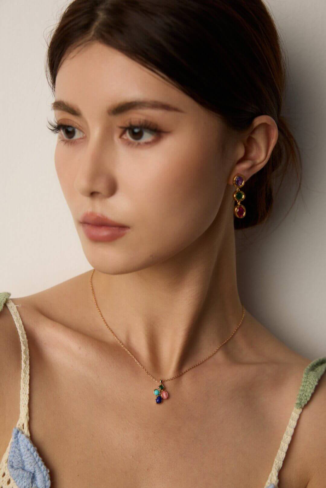 Woman showcasing the colorful pendant with a casual white shirt or daytime outfit.