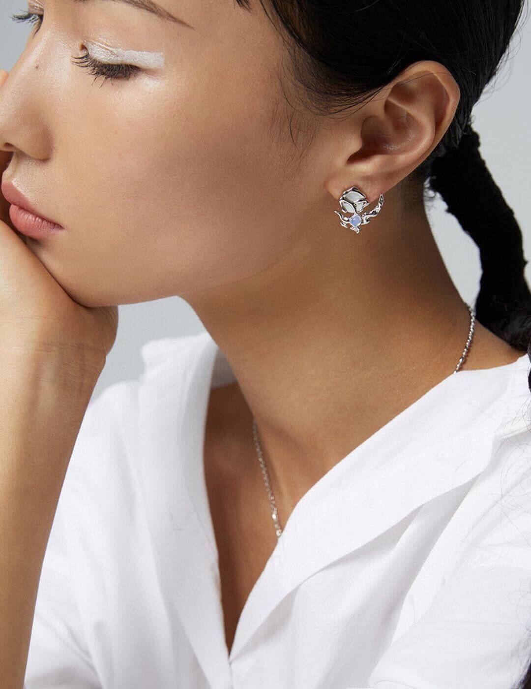 Woman wearing asymmetric opal and mother of pearl earrings