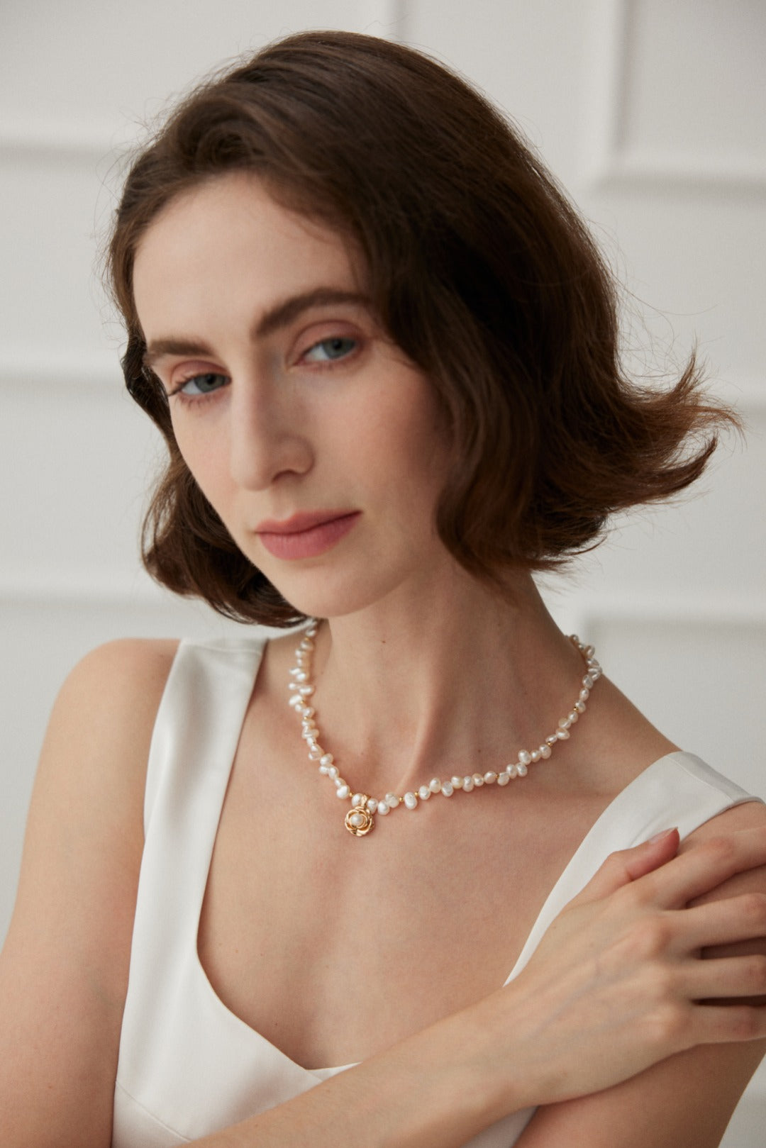Woman wearing the camellia and natural pearl necklace, elegant neck close-up.