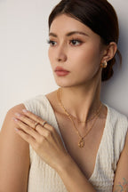 Woman wearing gold jewelry against a neutral background