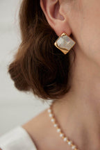 Side view of mosaic shell earrings on model, showcasing unique geometric design against skin.
