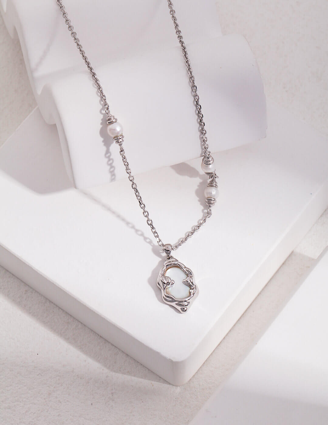 Silver necklace with a heart-shaped pendant on a white surface