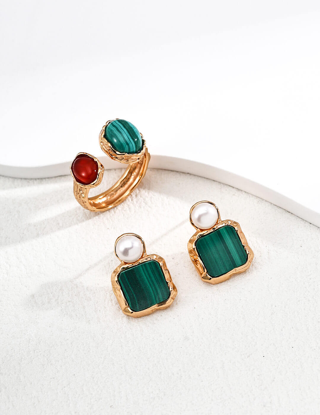 Set of earrings with green malachite and pearl accents on a white background