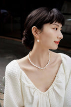 A smiling model looking over her shoulder, showcasing the vintage baroque pearl earrings that convey a sense of tenderness and grace.