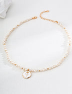 Natural pearl and enamel rose necklace in sunlight, highlighting the pearl's glow and rose's vibrant color.