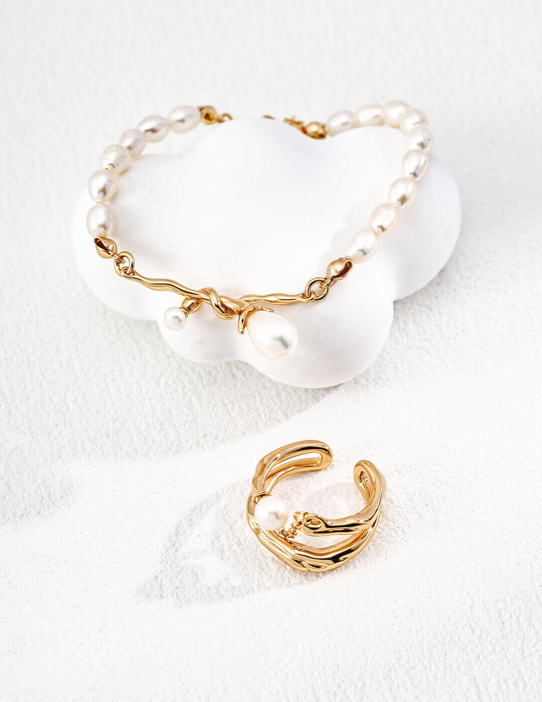 Gold bracelet and ring on a white background