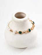 Flat lay of the bracelet showing the pearl, malachite, and vintage gold chain.