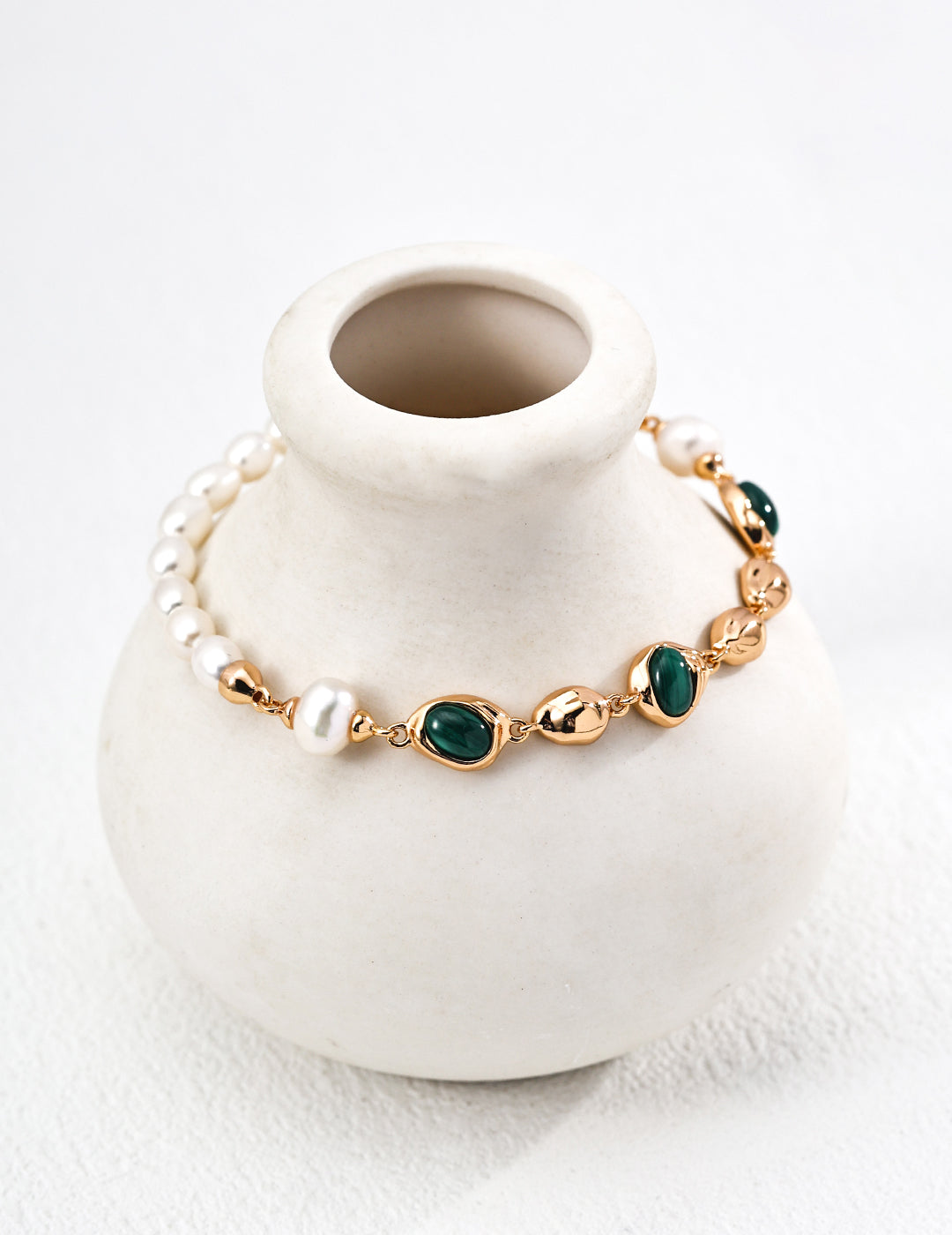 Flat lay of the bracelet showing the pearl, malachite, and vintage gold chain.