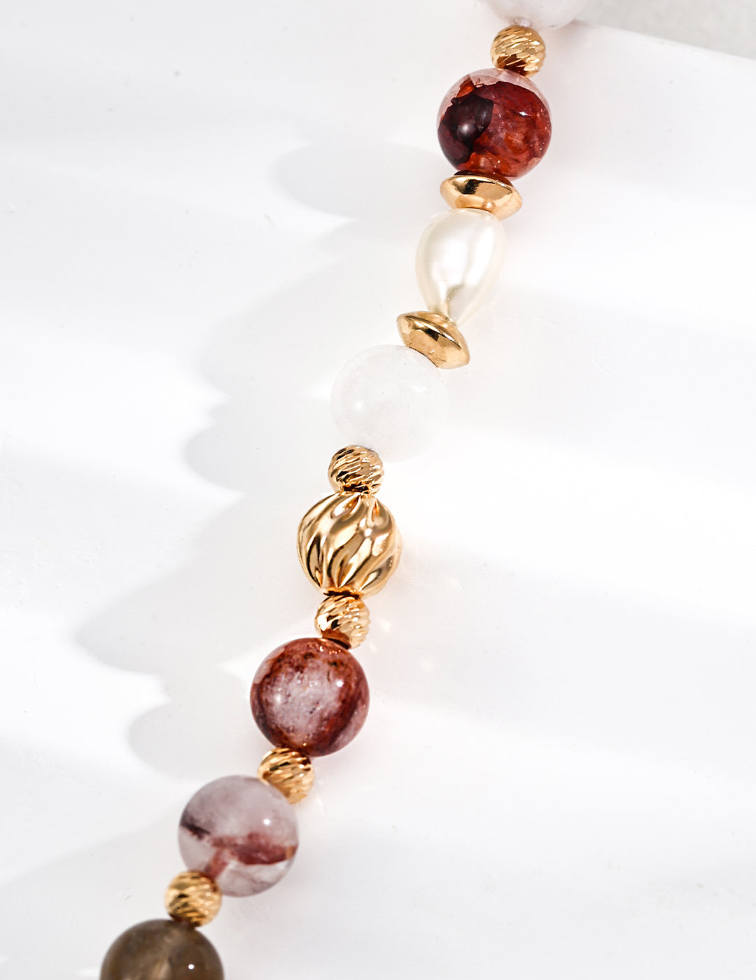 Flat lay of the bracelet showing the red agate, pearl, faceted and twisted beads.