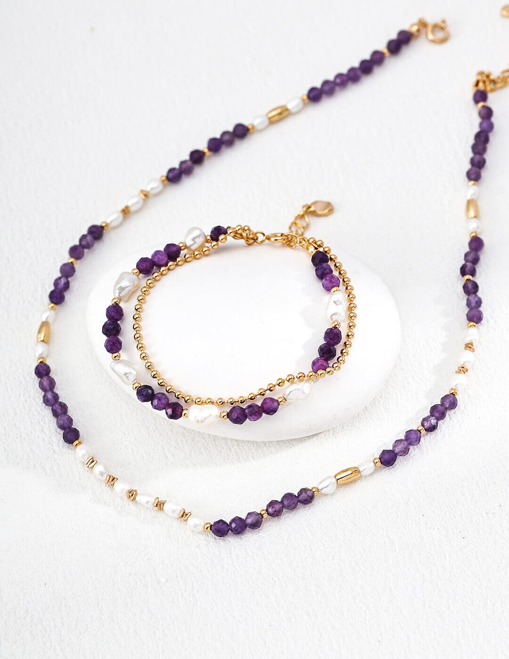 Purple beaded necklace and bracelet set on a white background