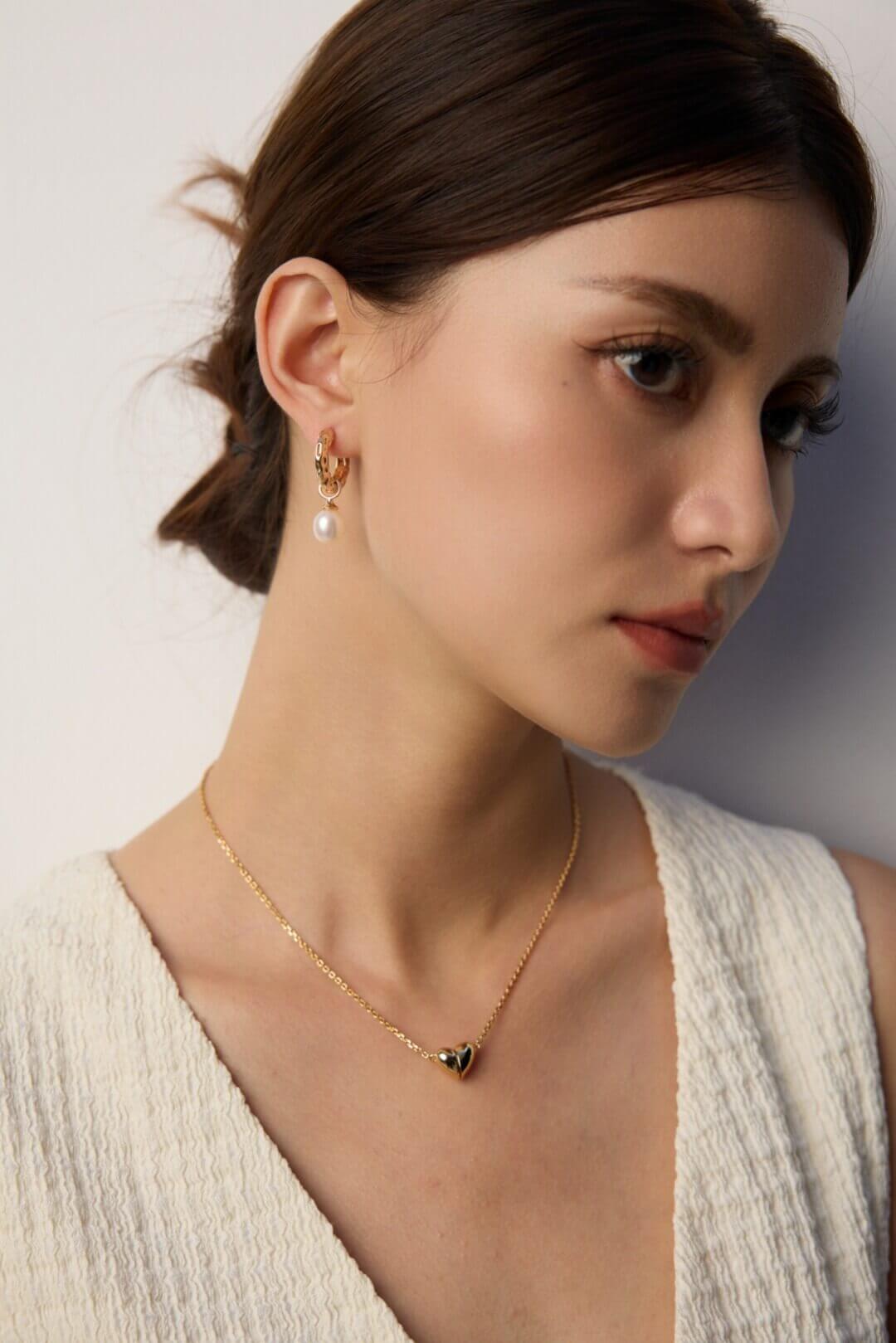 Model wearing the wood grain and pearl earrings in natural sunlight, evoking the beauty and warmth of nature.