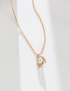 Gold necklace with a blue gemstone and pearl on a white background