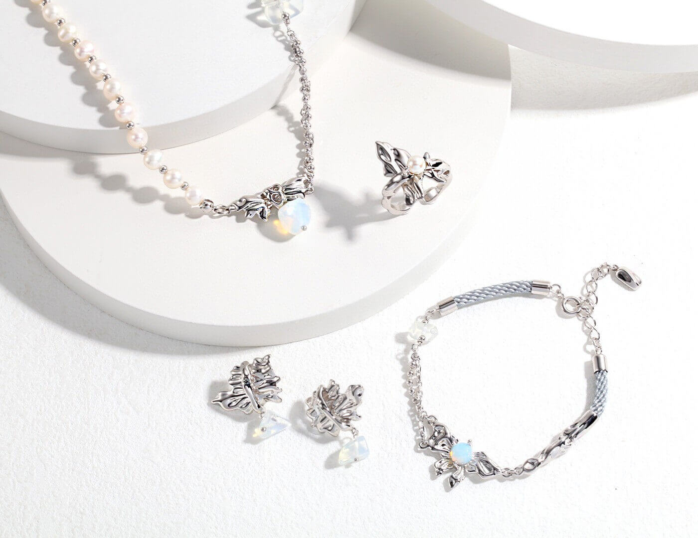 Silver jewelry set including necklace, earrings, and bracelet on a white background