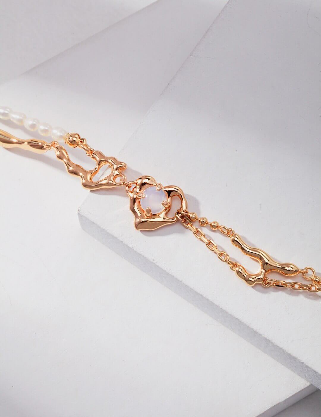Rose gold bracelet with a heart-shaped clasp on a light gray background