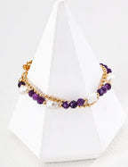 Necklace with purple beads and gold chain on a white stand