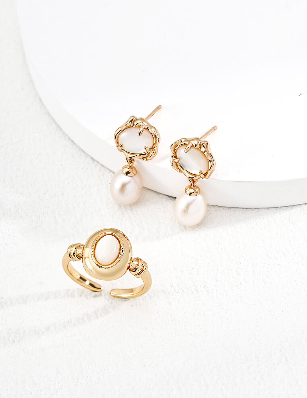 Gold earrings with pearl drops on a white surface