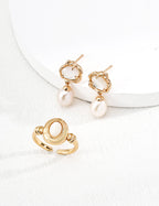 Gold earrings with pearl drops on a white surface