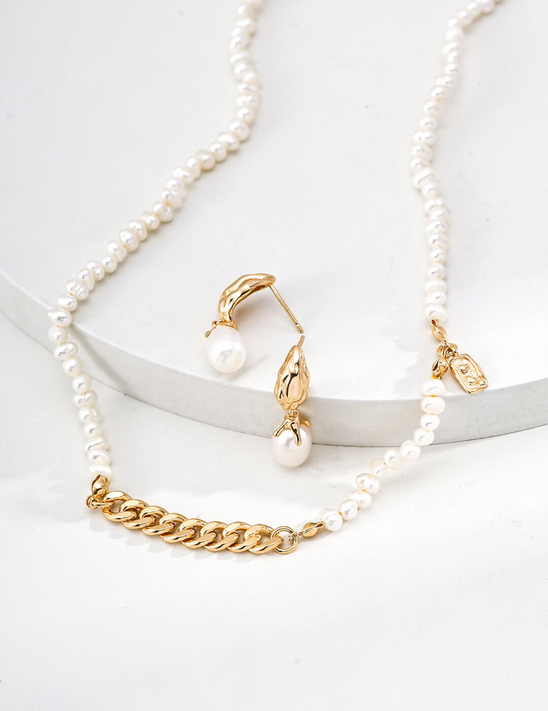 Pearl necklace with gold chain and matching earrings on a white background