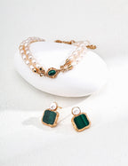 Jewelry set with green gemstone earrings and gold bracelet on a white background