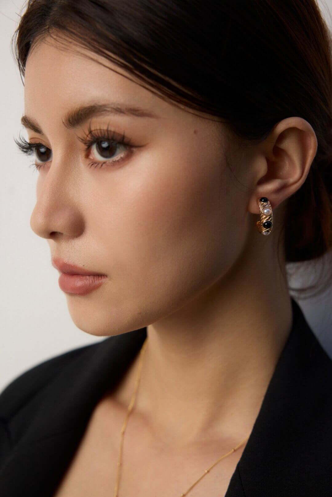 Vintage pearl and onyx stud earrings complementing professional business attire with timeless style.