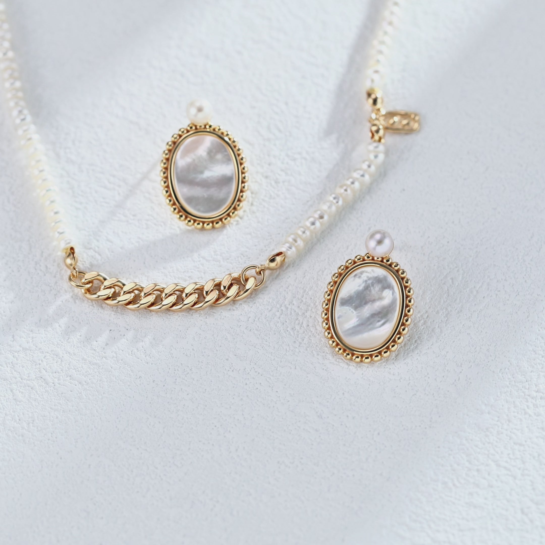Minimalist pearl and shell earrings held in hand to show perfect size and delicate proportion for everyday elegance.