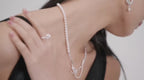 The asymmetric pearl drop earrings in motion, capturing the dynamic beauty of the design on a turning model.