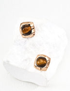Gold earrings with tiger's eye stones on a white background