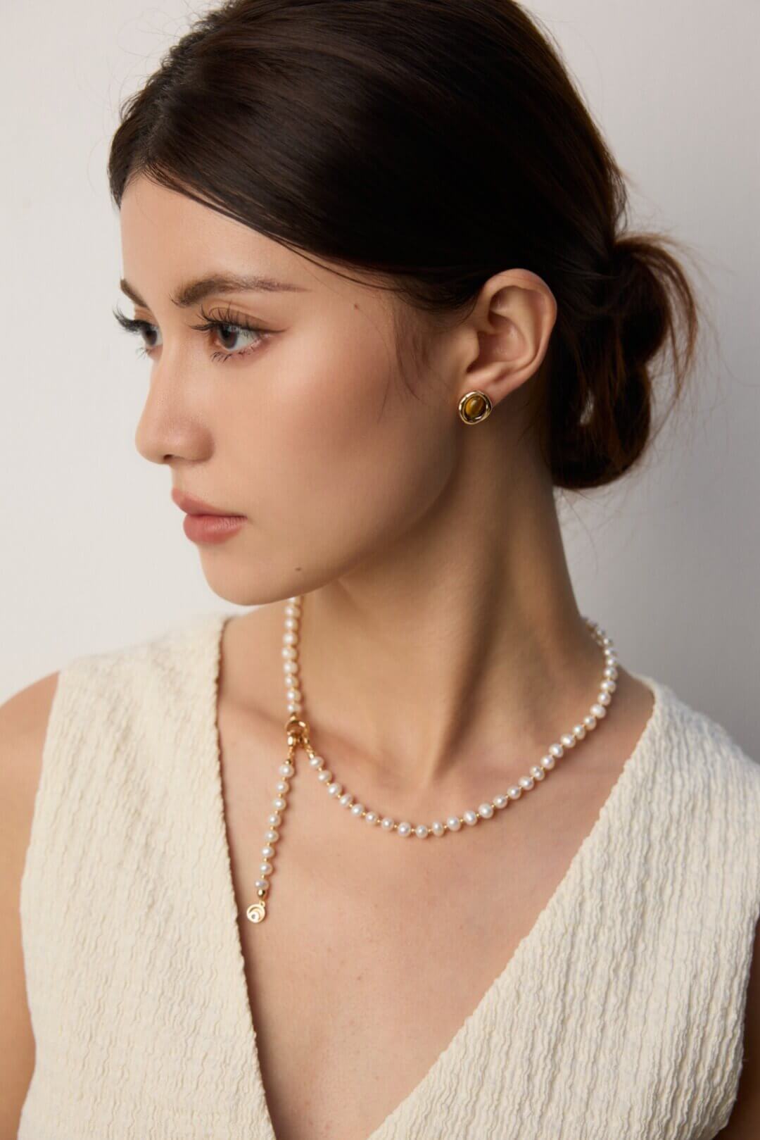 Woman wearing the minimalist Tiger's Eye stud earrings.
