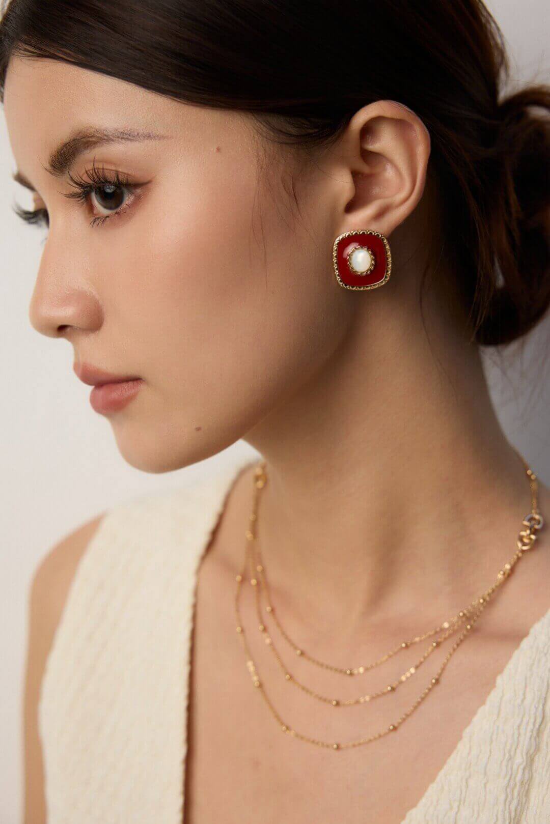 Side view of the shell and enamel drop earrings worn, showing their elegant dangle.