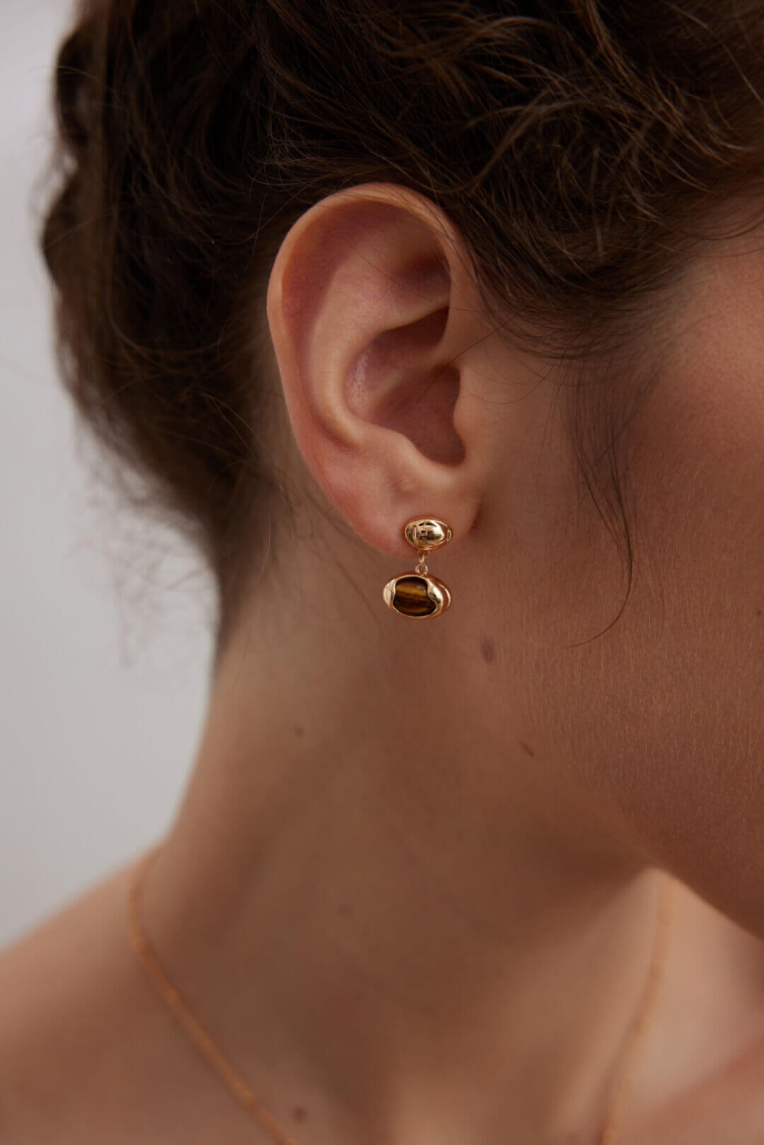 15mm Tiger Eye earrings on model's ear, demonstrating perfect proportion and golden-brown band beauty.