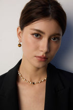Woman wearing a pearl necklace and earrings against a plain background