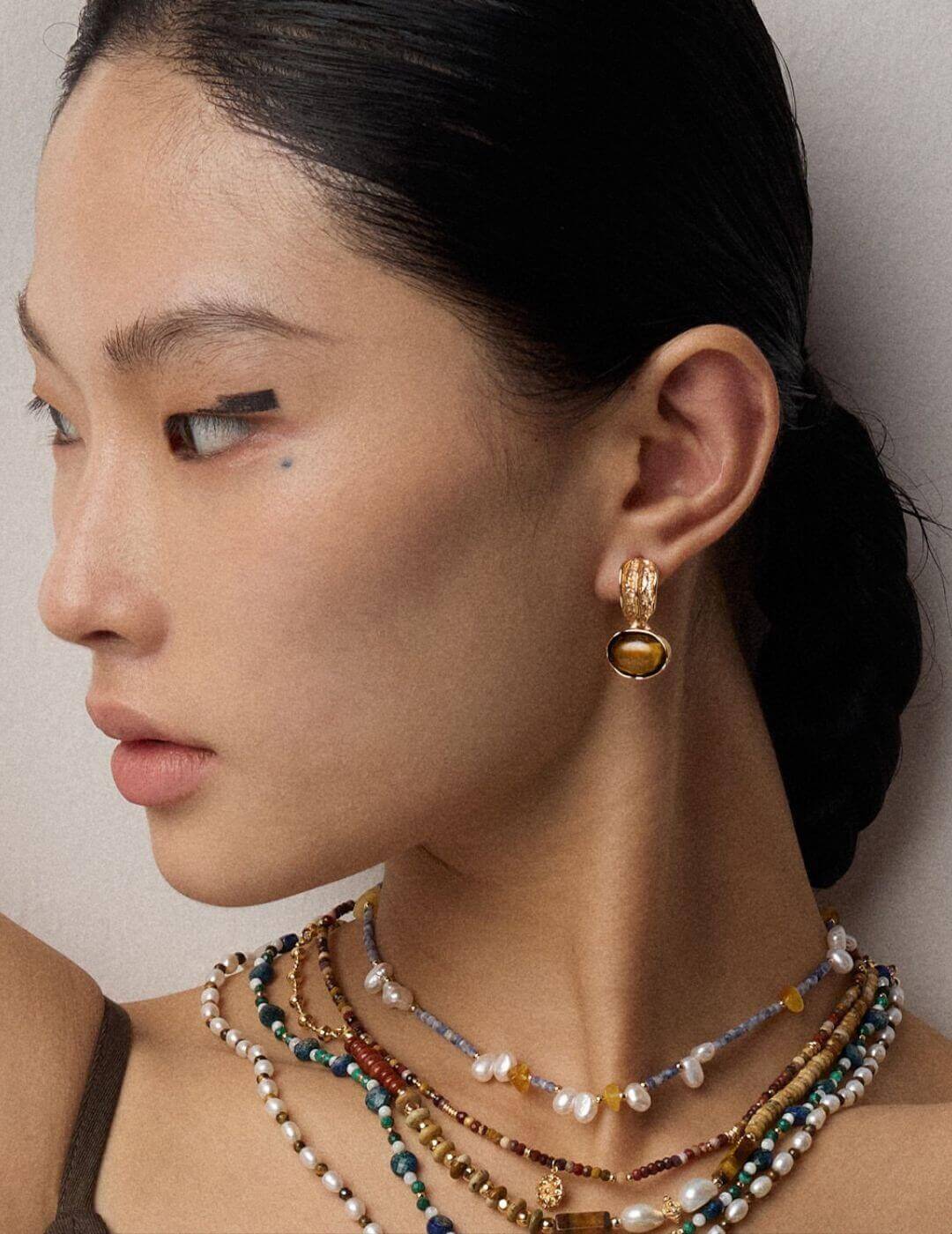 Tiger's Eye earrings in natural sunlight, showcasing their chatoyancy and golden brown hues on model.