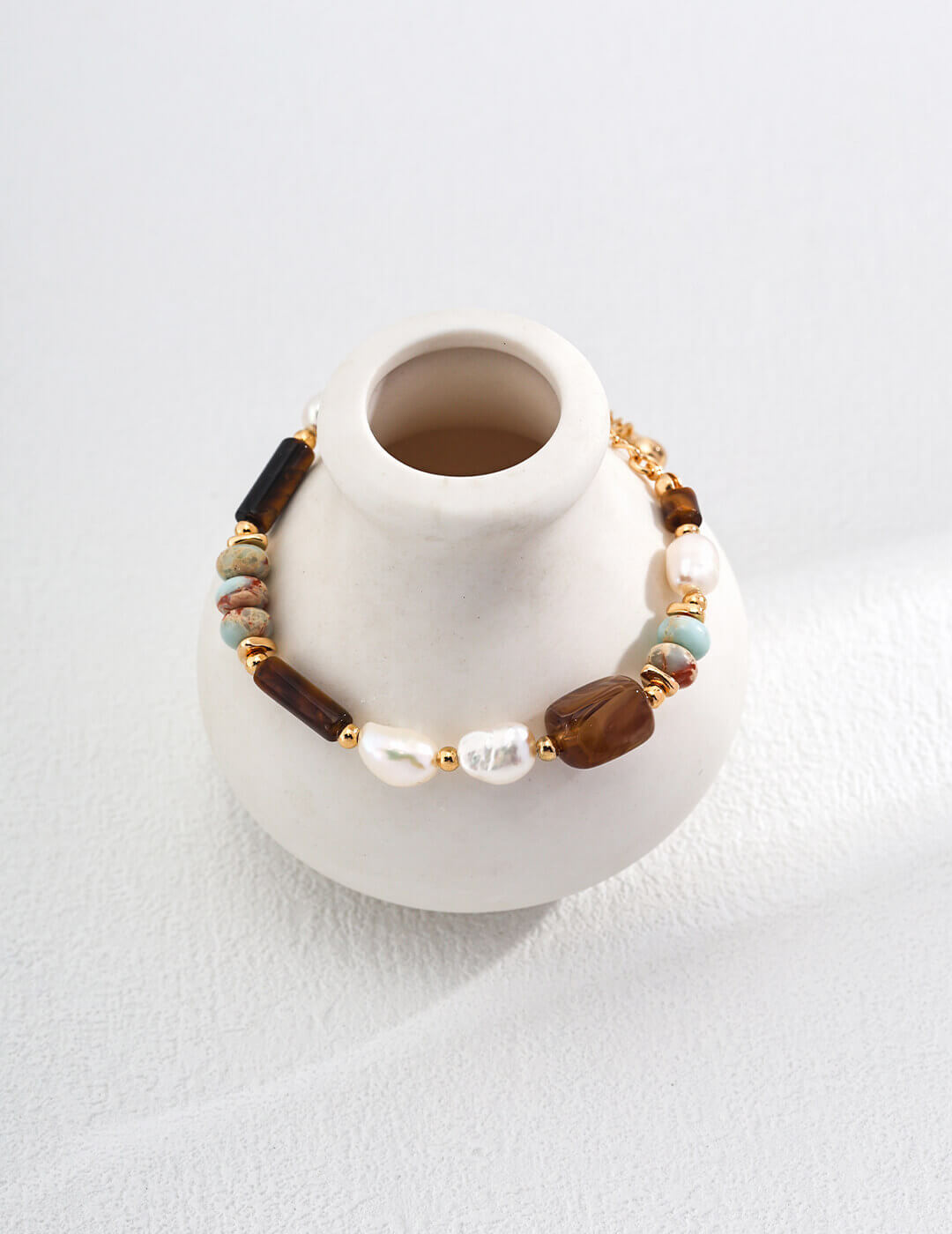 Bracelet with beads on a white vase against a white background