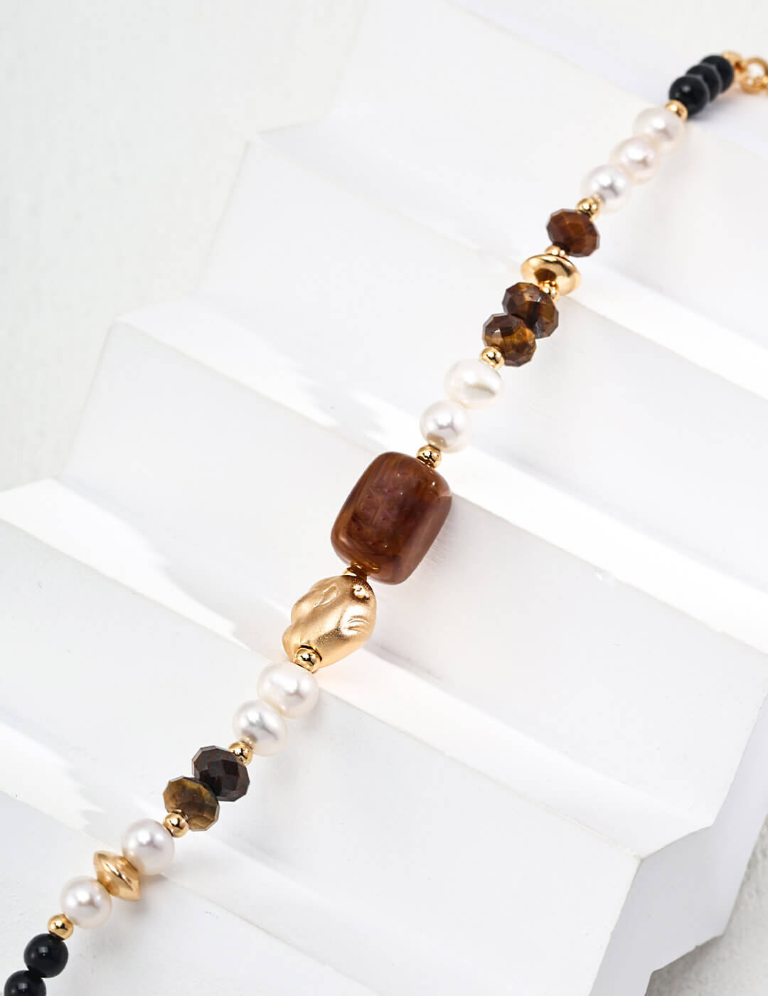 Necklace with brown, gold, and black beads on a white background