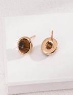 Gold earrings with tiger's eye stones on a white background