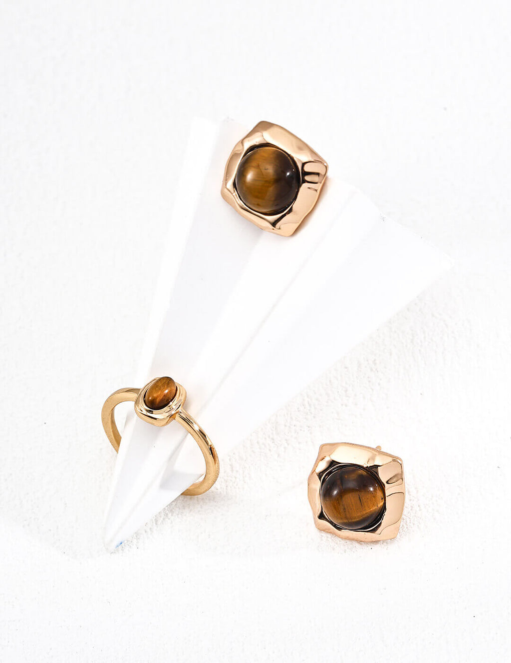 Gold earrings with brown gemstones on a white background