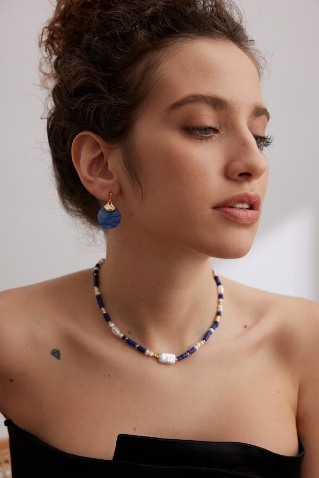 Close-up side view of a woman wearing the blue Aventurine fan earrings.