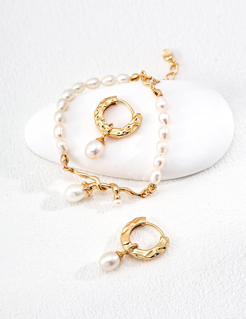 Gold hoop earrings with pearls on a white background
