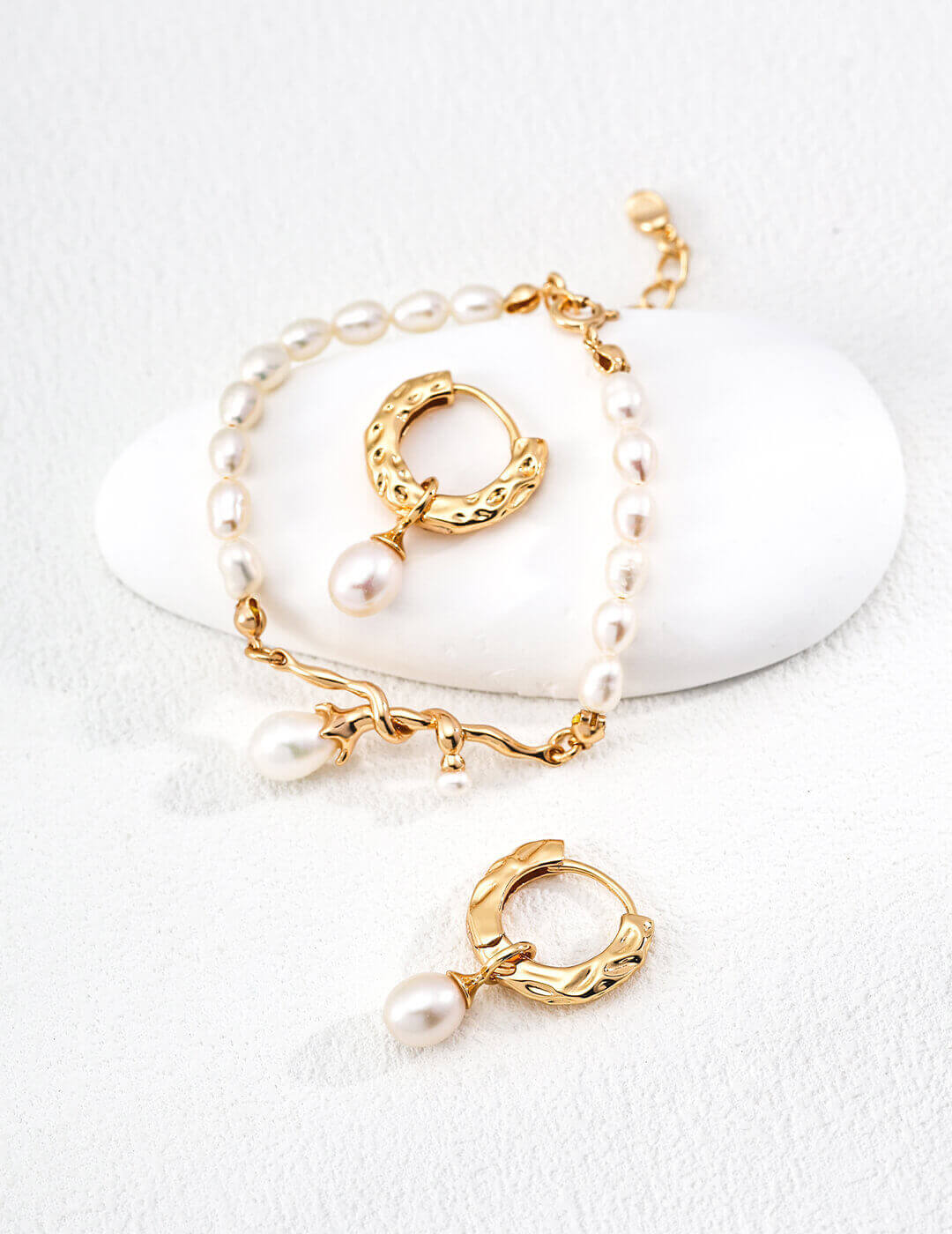 Gold hoop earrings with pearls on a white background