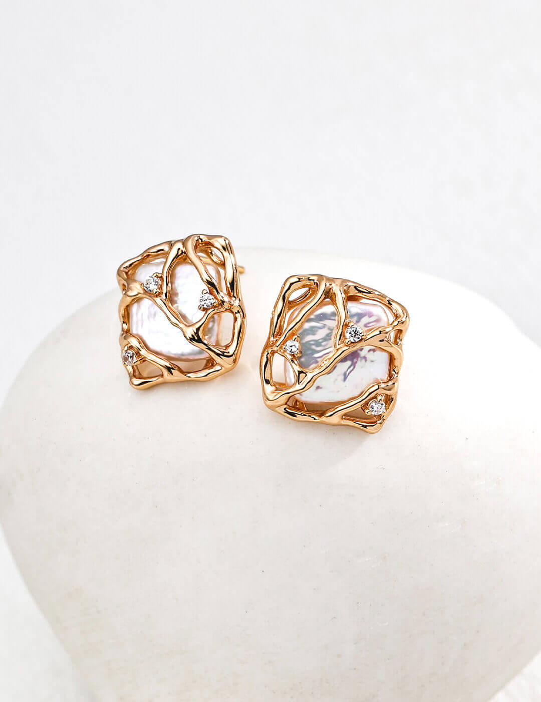 Rose gold earrings with clear gemstones on a white surface