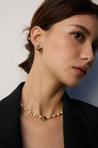 Woman wearing a pearl necklace and earrings against a neutral background