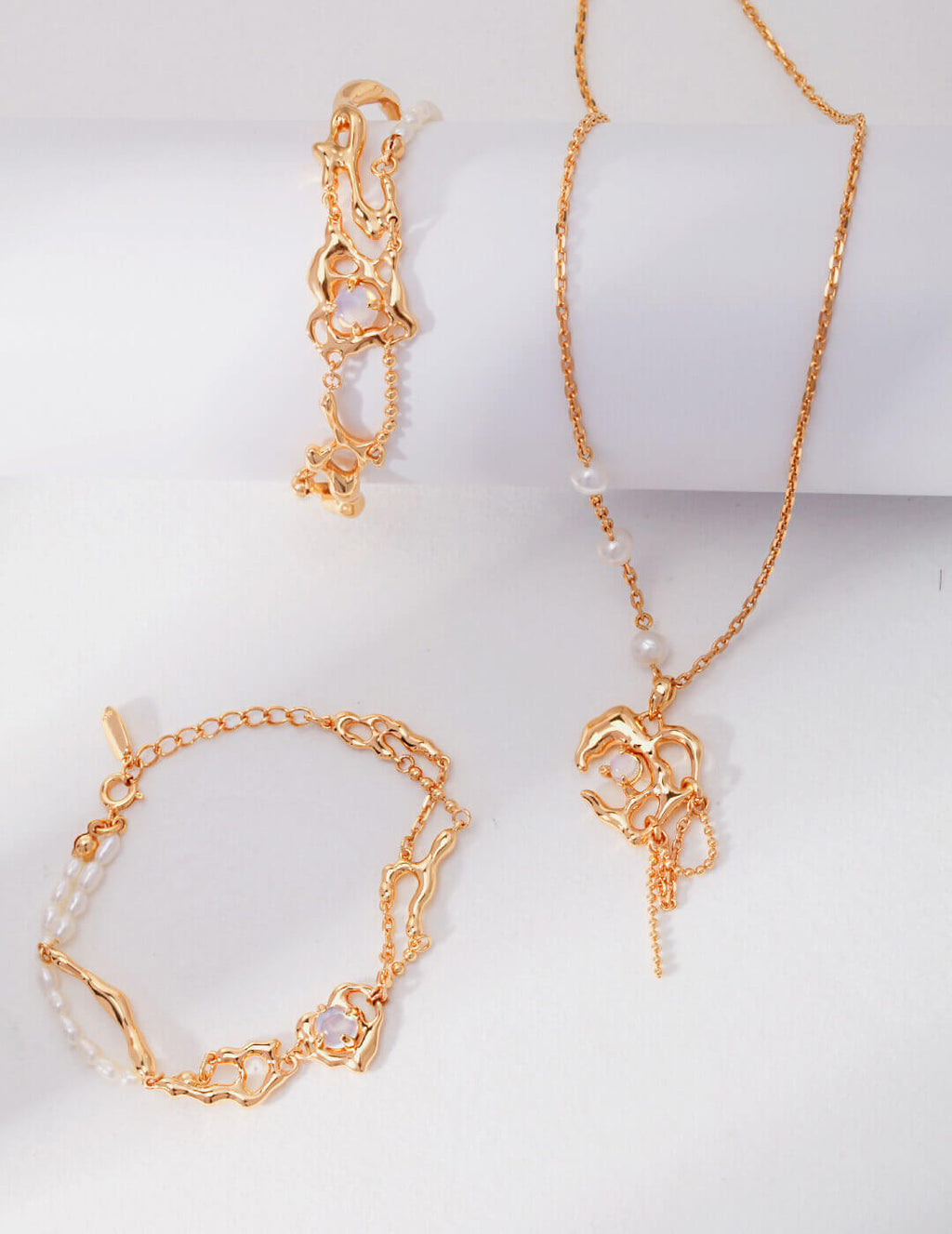 Gold jewelry set including a necklace and two bracelets on a white background