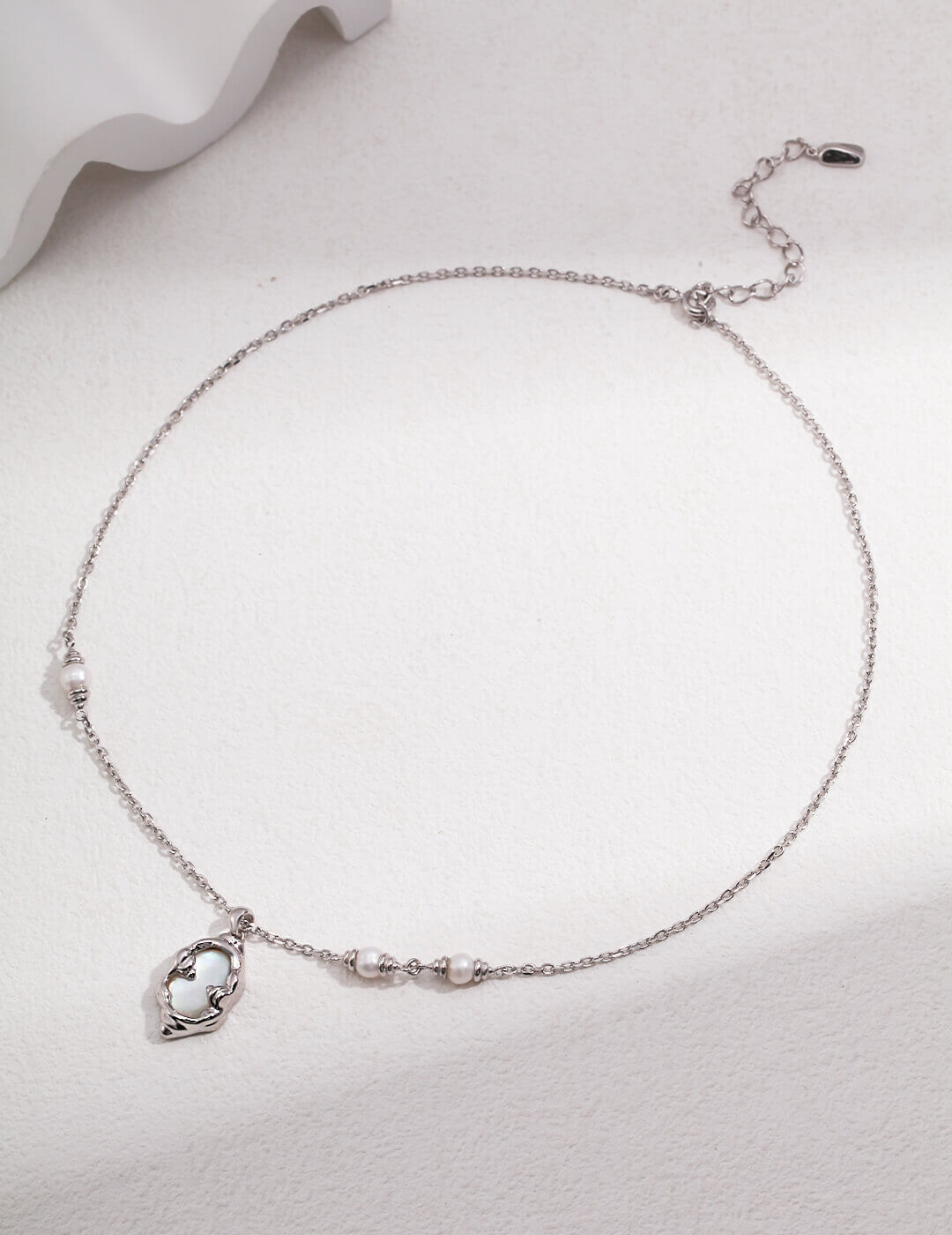 Silver necklace with a heart-shaped pendant on a light gray background