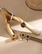 Gold jewelry set with necklace, bracelet, and earrings on a wooden branch.