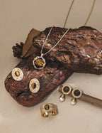 Gold jewelry set including necklace, earrings, and ring on a wooden surface.