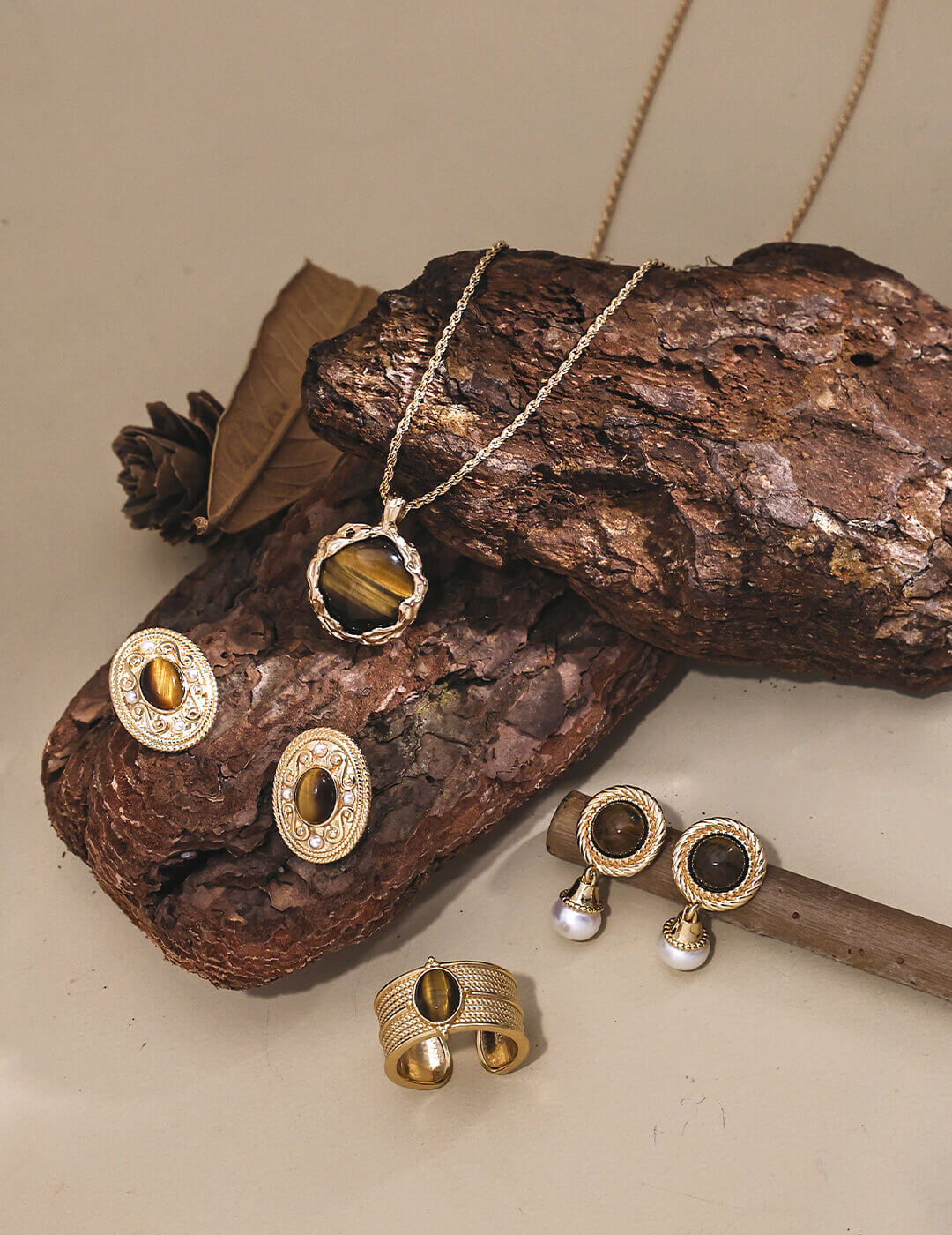 Gold jewelry set including necklace, earrings, and ring on a wooden surface.