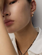 Side view of white gold pearl and onyx stud earrings on model, highlighting fresh vitality.